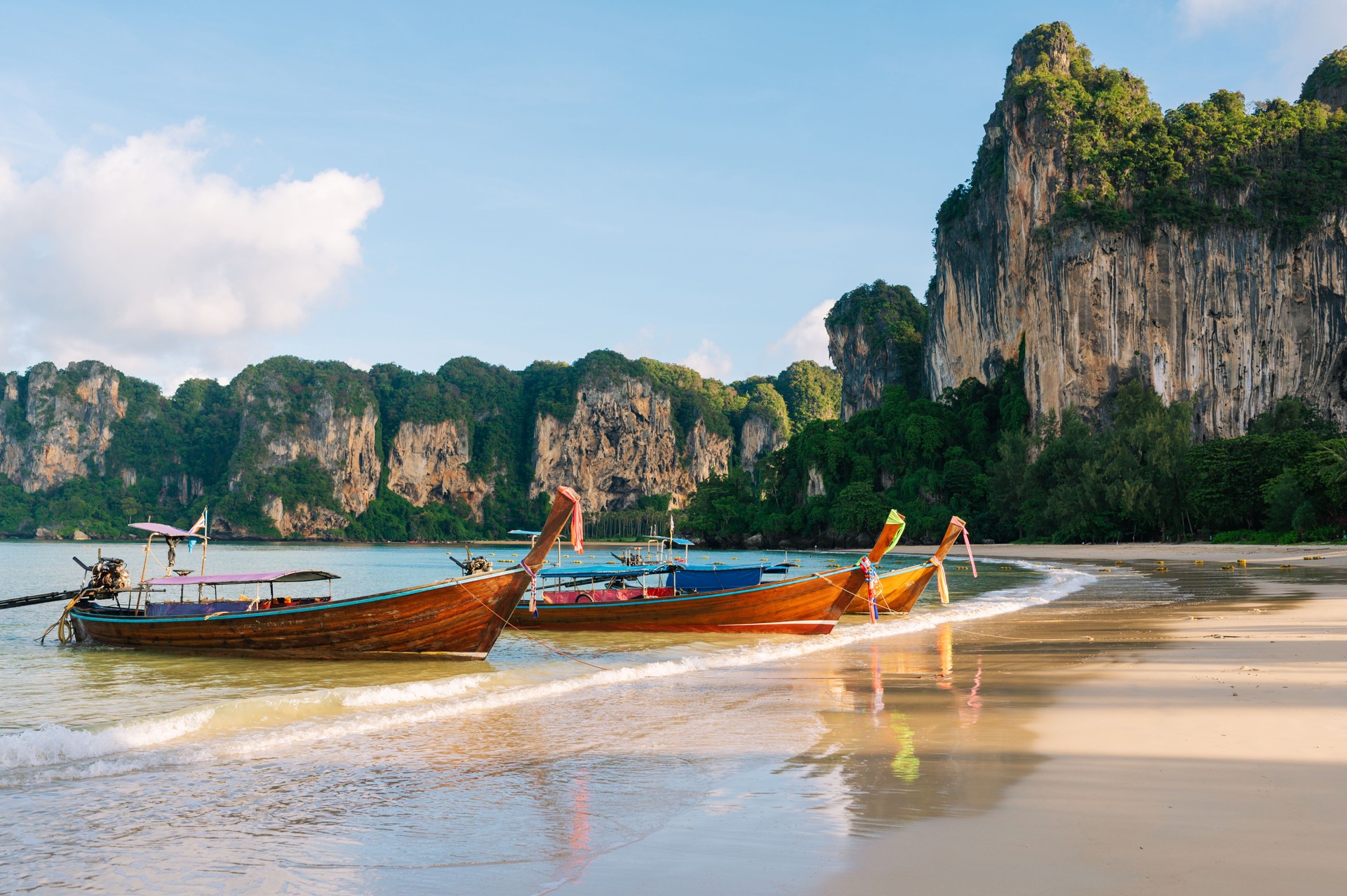 Longtail Boats Anchored Beneath Krabi’s Majestic Cliffs railay krabi thailand