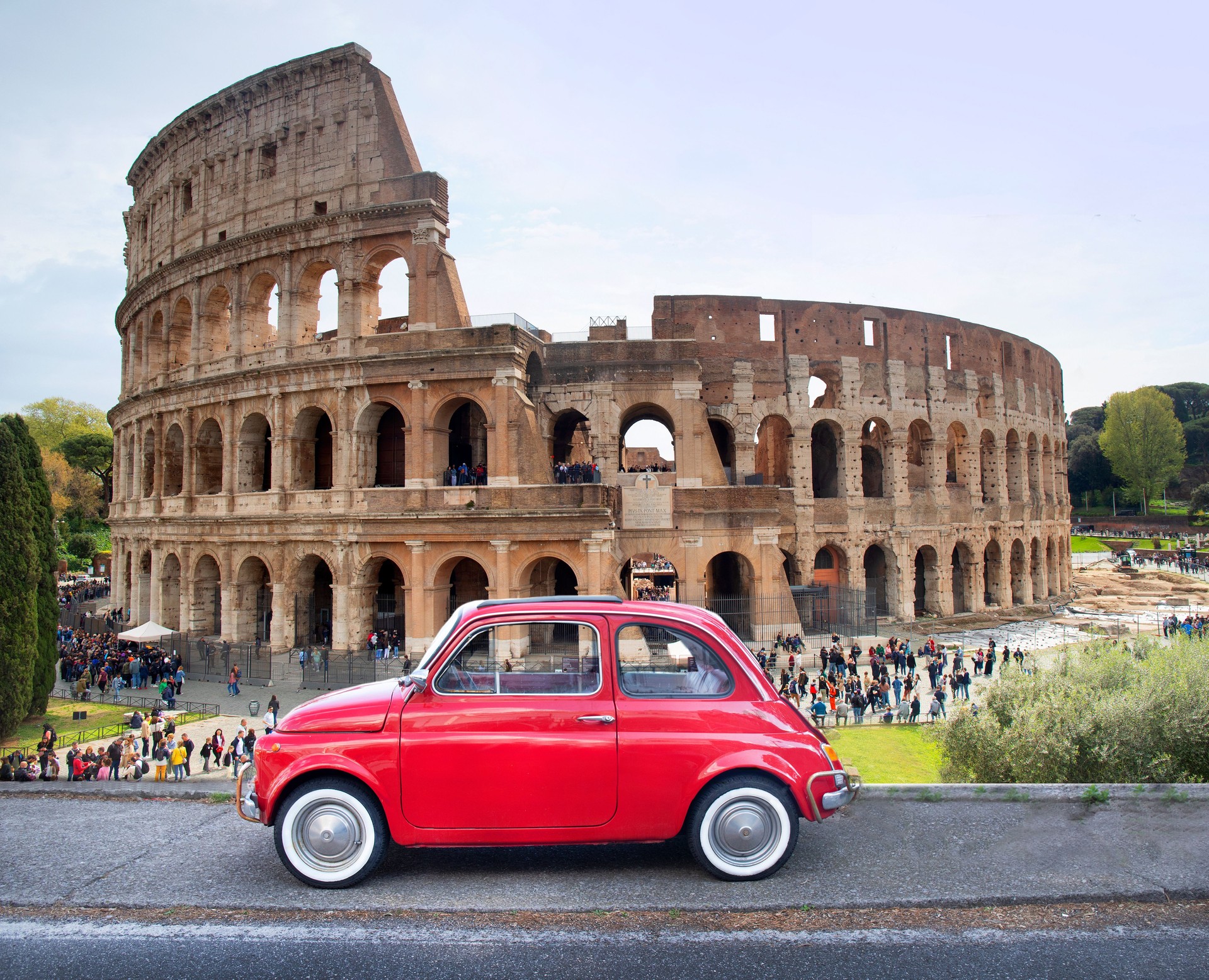 Rome,  Coliseum, with red old small car foreground.
composite image