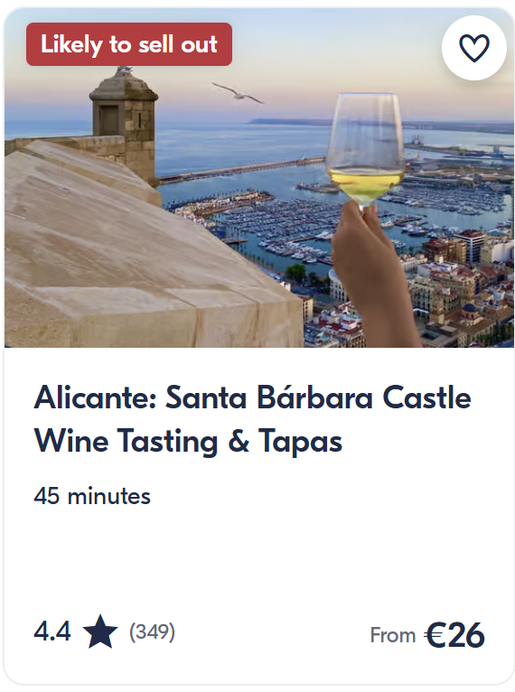 Glass of white wine overlooking Alicante harbour from Santa Bárbara Castle at sunset – wine tasting and tapas experience.